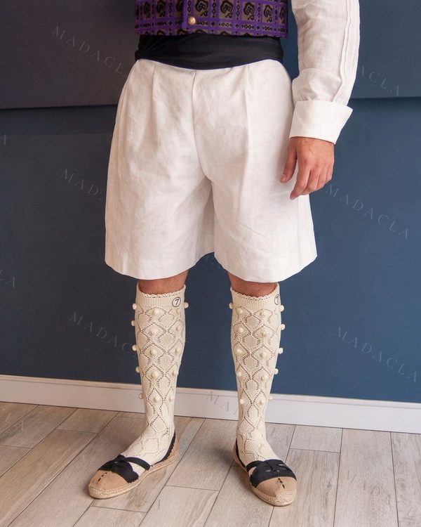 Calcetas de punto calado en blanco roto, altas hasta la rodilla, con diseño de rombos y madroños. Llevan el puño festoneado y el número 7.