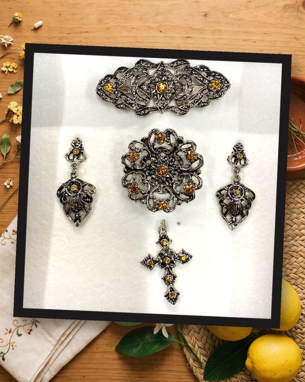 Aderezo plata y ámbar: pendientes largos, broche redondo, pasador para el pelo y cruz, en metal plateado envejecido con cristales color ámbar.