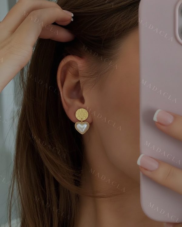 Pendientes dorados con una pieza superior redonda y una inferior colgante en forma de corazón blanco nacarado, con un borde dorado.
