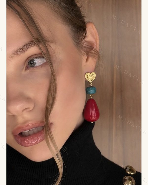 Pendiente largo con corazón dorado labrado, una cuenta turquesa y una gota roja brillante.