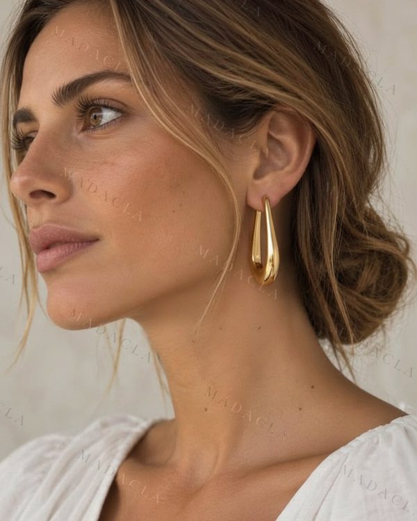 Pendiente dorado con forma de gota alargada y gruesa, con acabado brillante.