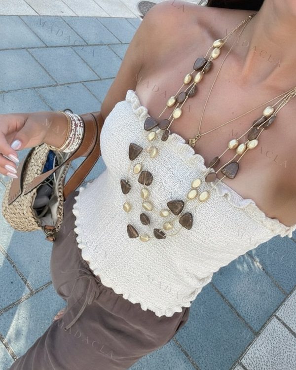 Collares largos de varias cadenas doradas con cuentas claras ovaladas y oscuras de forma irregular.