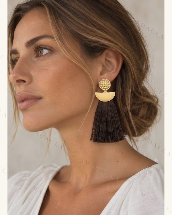 Pendientes largos dorados con disco texturizado y media luna, con borla de hilos oscuros.