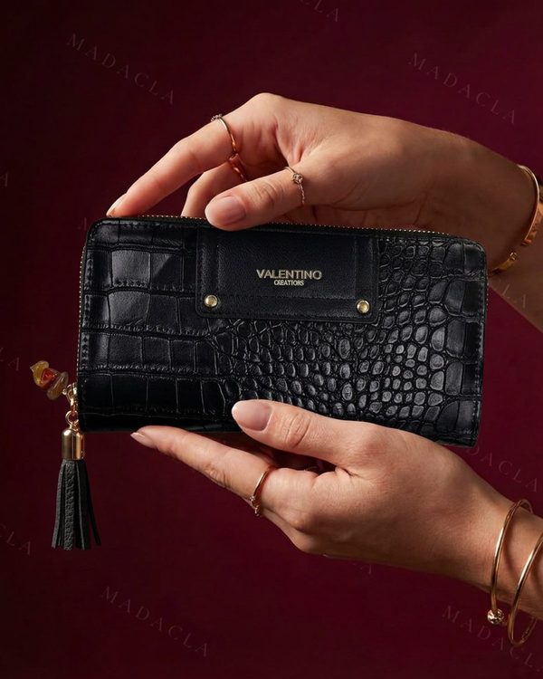 Monedero negro rectangular con grabado efecto cocodrilo y cremallera perimetral. Lleva la placa VALENTINO CREATIONS y dos remaches dorados.