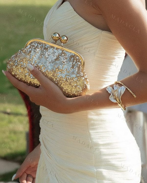 Bolso de mano dorado cubierto de lentejuelas. Cierre de boquilla metálico con dos bolas doradas.