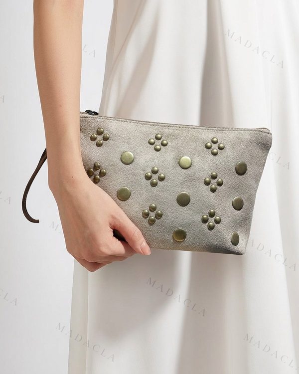 Neceser gris de textura mate con cierre de cremallera. Adornado con remaches metálicos redondos y grupos de cuatro en tono bronce.