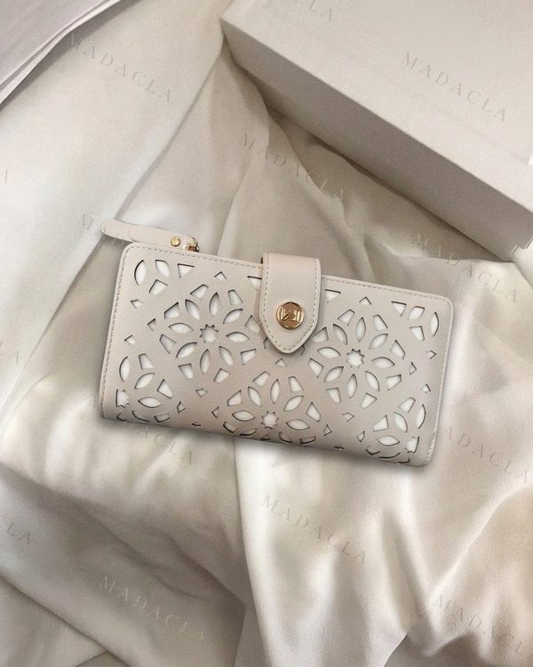Cartera rectangular beige claro con troquelado floral calado. Cierre de solapa con botón dorado y asa de muñeca lateral.