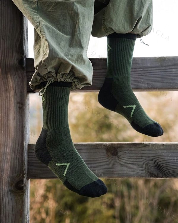 Calcetines largos verde oscuro con puntera y talón negros, un dibujo geométrico verde claro y la parte superior acanalada.