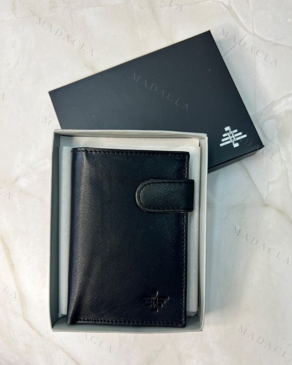 Cartera negra de piel compacta con solapa de cierre y botón. Presenta un logo grabado en la parte inferior.