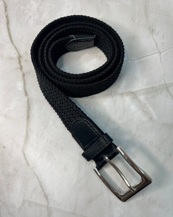 Cinturón unisex de goma trenzada negra con punteras y pasador negros. Cierre con hebilla metálica rectangular plateada.