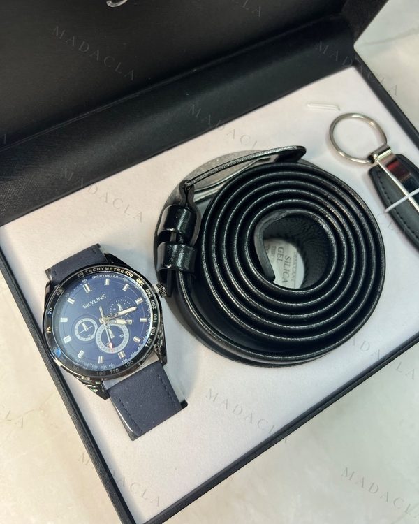 Pack de tres piezas: reloj con esfera azul y grabado SKYLINE, correa azul, cinturón negro con hebilla metálica y llavero negro.