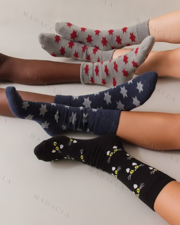Calcetines de punto: un par gris con estrellas rojas, otro azul marino con estrellas grises, y un tercero negro con caras de gatos amarillas.