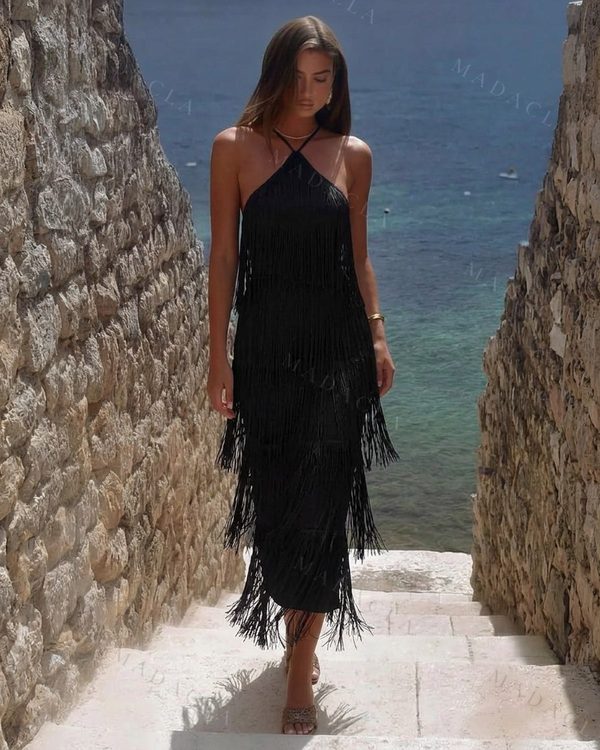 Vestido negro de corte recto con escote halter y espalda abierta. Presenta flecos largos desde la cintura hasta casi el tobillo.