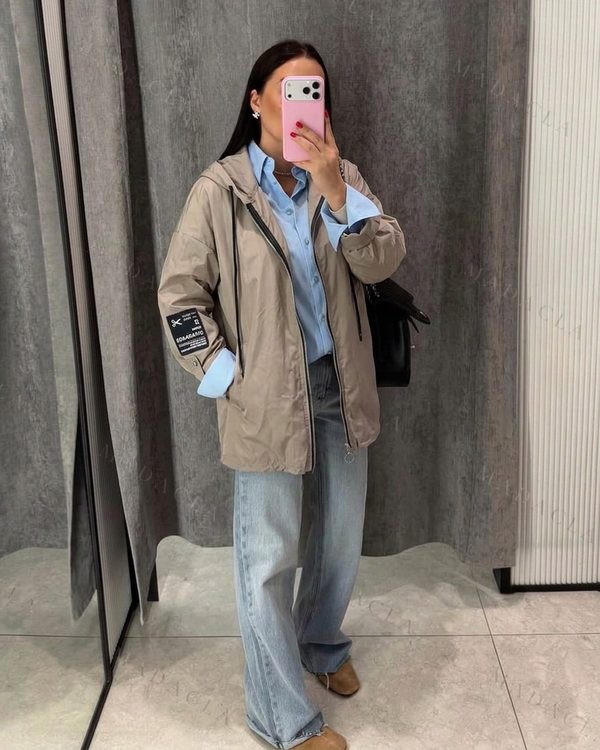 Chaqueta beige de corte amplio y largo por la cadera. Con capucha, cremallera negra, cordones y parche MADAME A. en la manga.