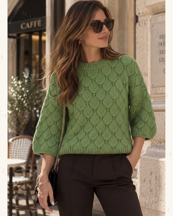 Jersey verde de punto con cuello redondo y manga tres cuartos ligeramente abullonada. Presenta motivo de rombos en relieve, bajo y puños acanalados.