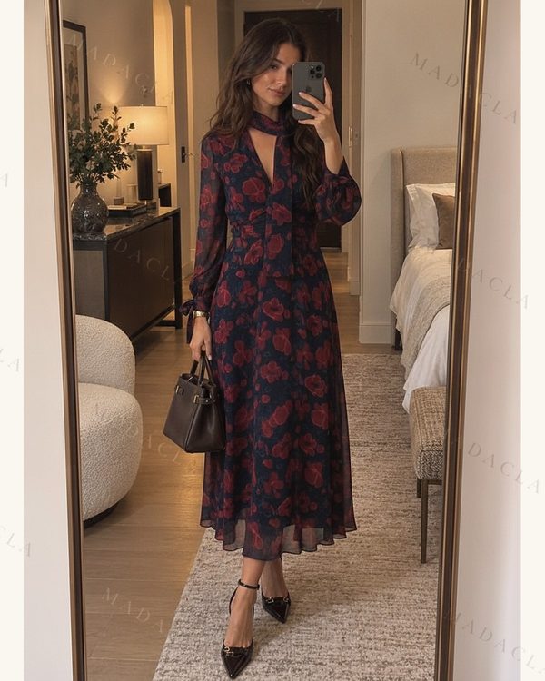 Vestido largo azul marino con estampado floral rojo, escote en V y lazada al cuello. Mangas largas terminadas en lazada y falda fluida.