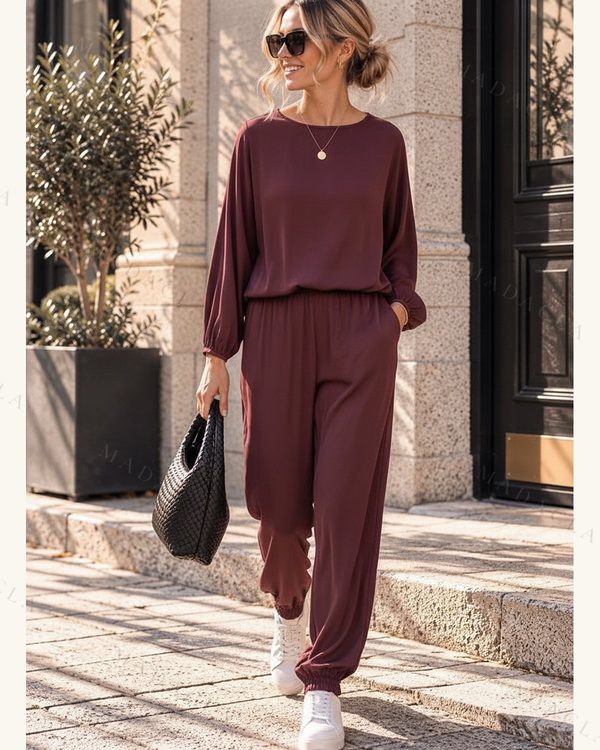 Conjunto burdeos de blusa fluida con escote redondo, mangas largas y puños fruncidos; pantalón jogger de cintura y bajos fruncidos.