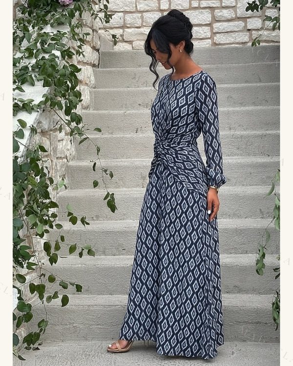 Vestido largo azul marino con estampado de rombos blancos, escote redondo, manga larga y detalle de tejido anudado en la cintura.