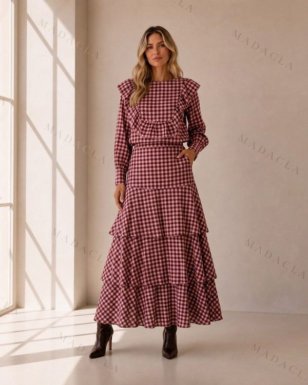 Conjunto de blusa y falda larga en cuadros vichy granates. La blusa lleva volantes en el pecho y hombros; la falda, de capas, tiene bolsillos.