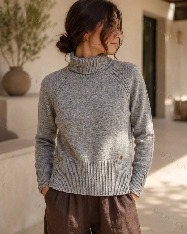 Jersey gris de punto con cuello vuelto, manga larga y botones en puños y laterales.