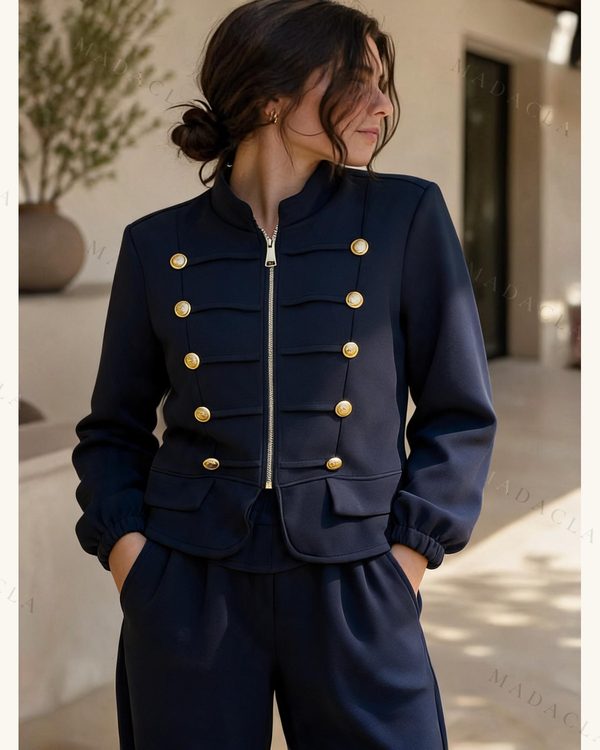 Chándal azul marino de chaqueta corta con cremallera central, cuello mao, botones dorados delanteros y trabillas, y pantalón largo de cintura elástica.