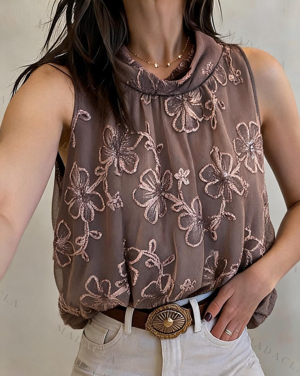 Blusa marrón sin mangas de corte recto con cuello vuelto drapeado y bordados de flores brillantes en tono a juego. También la tenemos en morado, crema y negro.