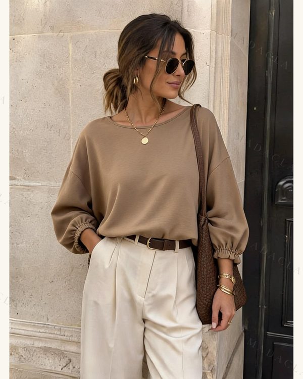 Blusa de color marrón claro, de manga larga abullonada con puños fruncidos y escote redondo.