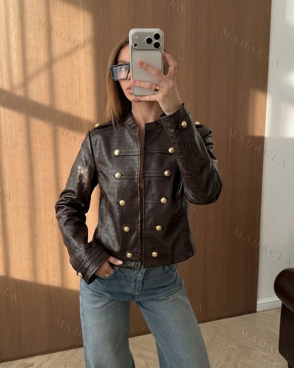 Chaqueta marrón chocolate con textura de cocodrilo y cuello de solapas. Presenta doble botonadura dorada en el frontal y los hombros, con un largo hasta la cadera.