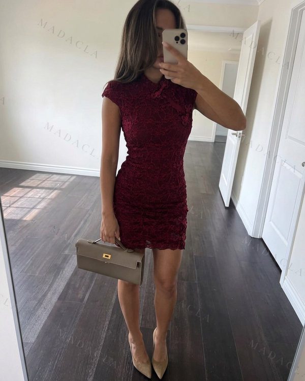 Vestido corto entallado en encaje calado burdeos con cuello mao, mangas cortas, nudos decorativos y bajo festoneado.