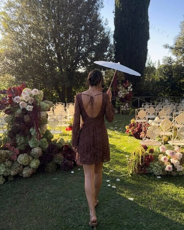 Vestido corto de tejido calado marrón oscuro con mangas largas. Presenta espalda abierta en pico y cordones finos en la parte superior.