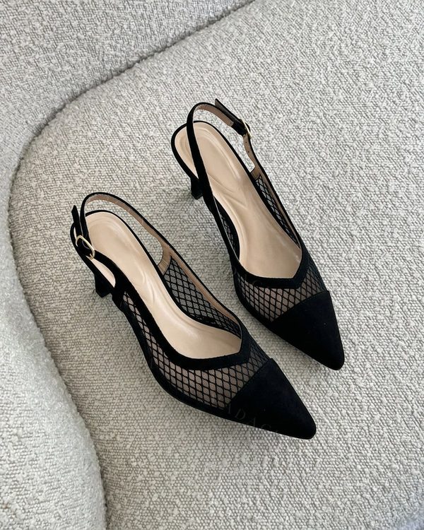 Zapatos destalonados negros de puntera afilada y tacón bajo. Llevan detalle de malla calada con patrón de rombos y tiras con hebilla.