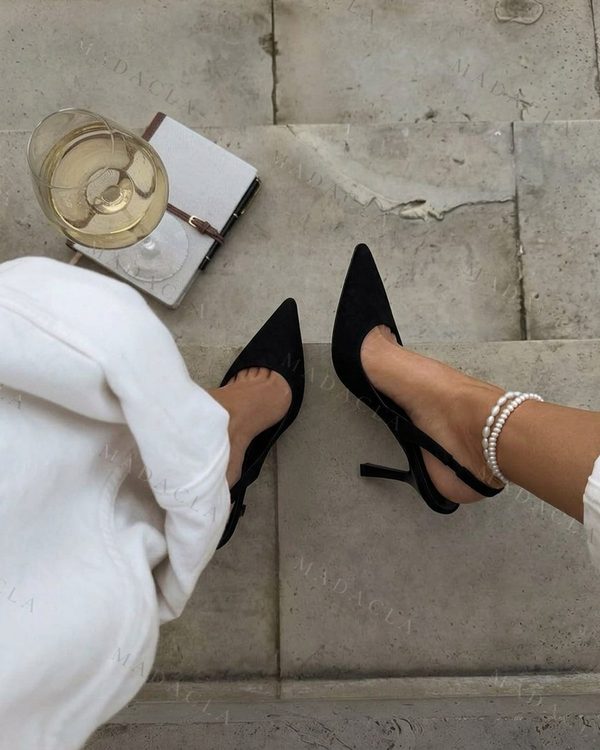 Zapatos negros de tacón con puntera afilada. Cuentan con un acabado mate y una tira trasera que deja el talón al descubierto.