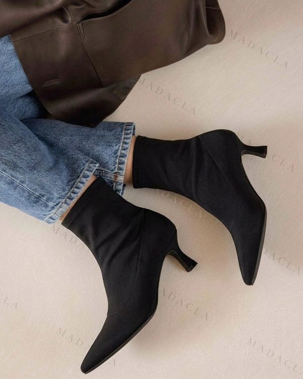Botines negros de tejido liso con punta afilada y tacón fino de altura media. El corte ajustado llega hasta el tobillo.