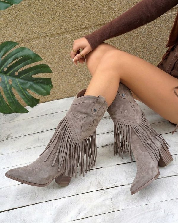 Bota alta gris topo de efecto serraje, con puntera afilada y tacón ancho. Presenta flecos largos laterales y detalles bordados en la caña.