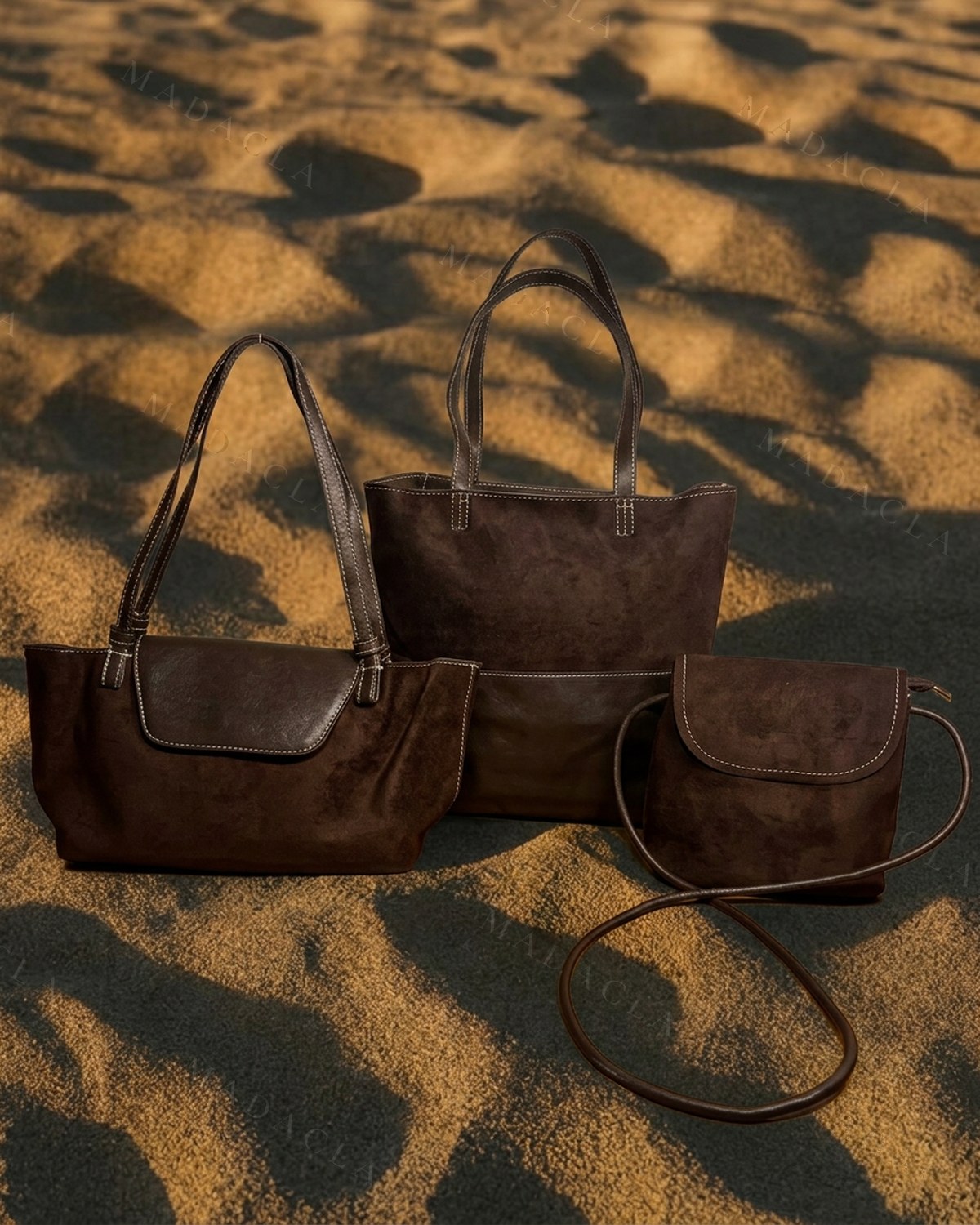 Conjunto en marrón chocolate, efecto ante con pespuntes en blanco: capazo grande de asas largas, bolso de hombro con solapa y bandolera pequeña de tira fina. Se venden por separado: puedes llevarte solo el que quieras, no hace falta el juego entero.