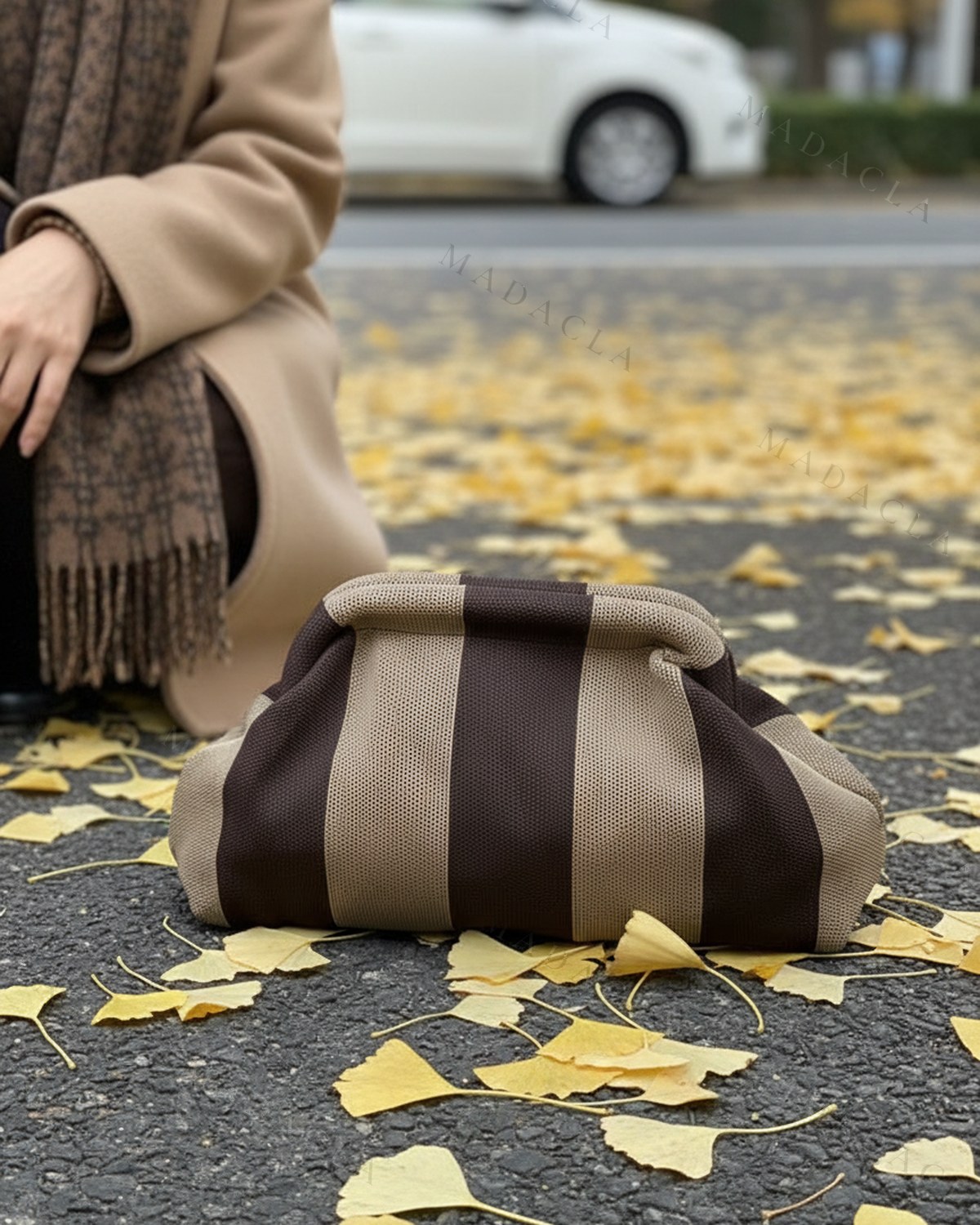 Bolso de mano tipo nube, de tejido calado en rayas anchas marrón chocolate y beige, con boquilla fruncida y sin asa.